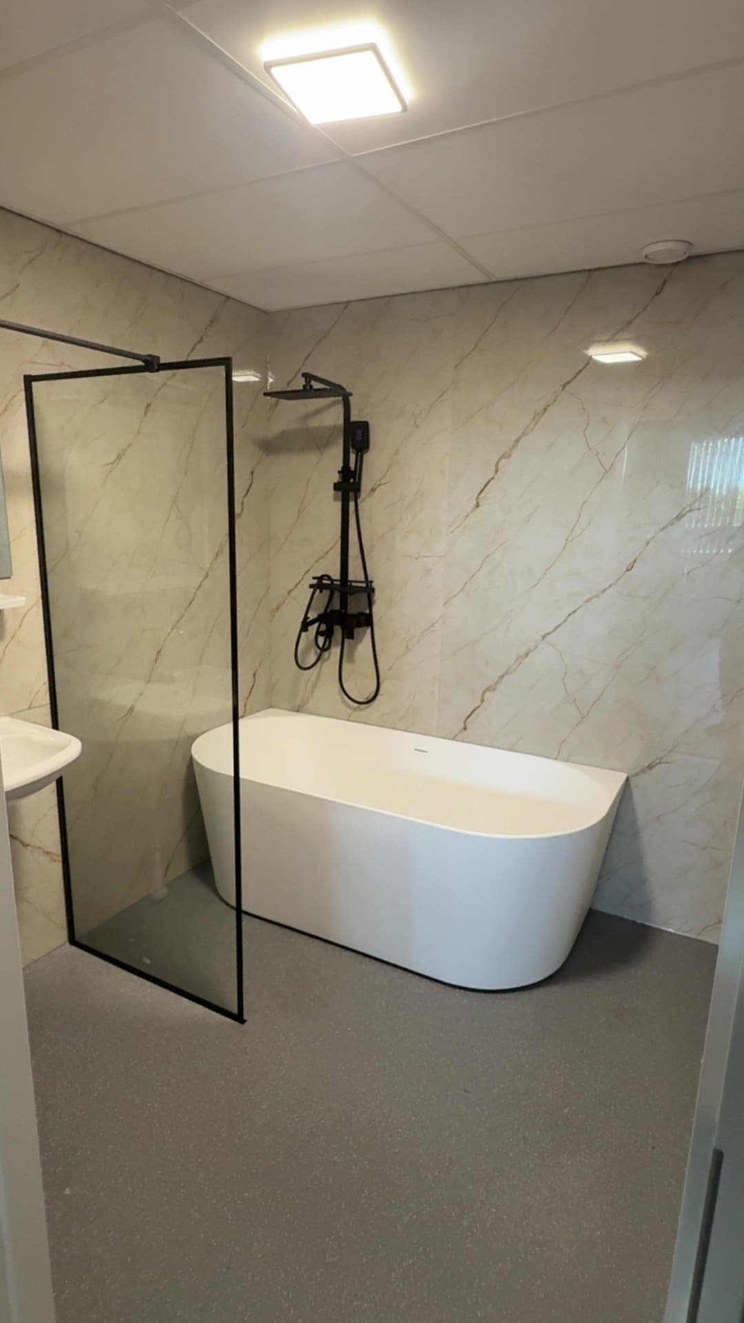 Luxe badkamer met marmerlook en ligbad — badkamerrenovatie in Rotterdam door Tjatjus